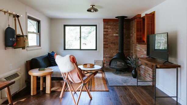 A cozy living room with a fireplace, a television, and a seating area with a sofa and chairs. - The Leeway - Two-Bedroom Suite (Mt Tremper)