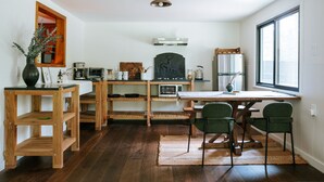A modern kitchen with wooden shelves, a dining table with chairs, and a large window. - The Leeway - Two-Bedroom Suite (Mt Tremper)