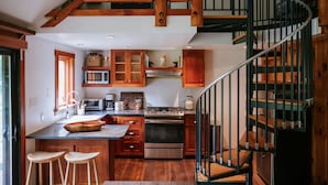 A kitchen with wooden cabinets, a stove, and a spiral staircase.
