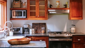 A modern kitchen with wooden cabinets, stainless steel appliances, and a marble countertop.
