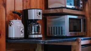 Una cocina con hervidor, cafetera y microondas sobre una encimera de madera.