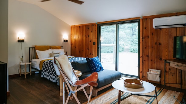 Una habitación acogedora con un sofá, una silla, una mesita y un televisor.