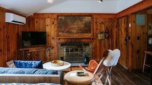Una sala de estar acogedora con chimenea, paredes de madera, un televisor de pantalla plana y un espacio de estar confortable.