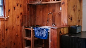 Una cocina compacta con paredes de madera, un lavamanos integrado y una pequeña encimera.