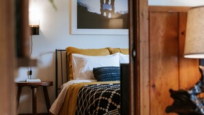 Ein Schlafzimmer mit Bett, Nachttisch, Lampe, einem gerahmten Bild an der Wand und einem Holzkopfteil.