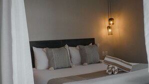 A neatly made bed with patterned pillows, a headboard, and a bedside lamp. - ROOM 7- Romantic 1 Bedroom Ocean Front Condo (El Rebase)