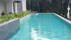 Una piscina rectangular con agua cristalina, rodeada por un bajo muro de piedra y follaje.