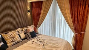 Un dormitorio con cama, cortinas y una pared con líneas verticales.