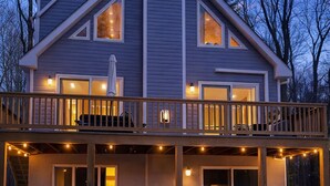 A modern two-story house with a balcony, outdoor seating, and a hot tub.