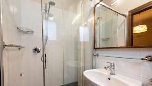 Un bagno moderno con cabina doccia in vetro, lavabo bianco e specchio con cornice in legno.
