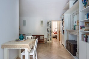 Un comedor con una mesa, sillas, un jarrón y una estantería.
