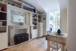 Una habitación con chimenea, estanterías, una mesa de comedor y vistas a través de una ventana.