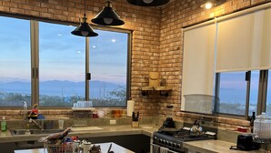 A modern kitchen with a large island, brick walls, and large windows offering a view of the mountains. - Amazing Views in the Luxury & Awesome house!   (B.C.S.)