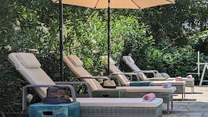 A row of sun loungers with cushions, a blue planter, and a white ladder against a backdrop of lush greenery. - La Galante  (Faugeres)