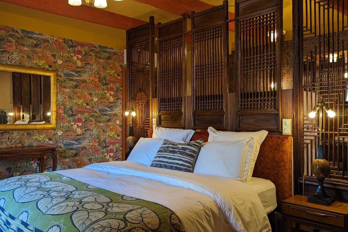 A traditional room with a bed, a mirror, and a decorative screen.