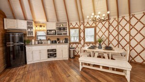 Eine kompakte Küche mit Holzschränken, einem Kühlschrank und einem Essbereich mit einer Bank und einem Tisch.