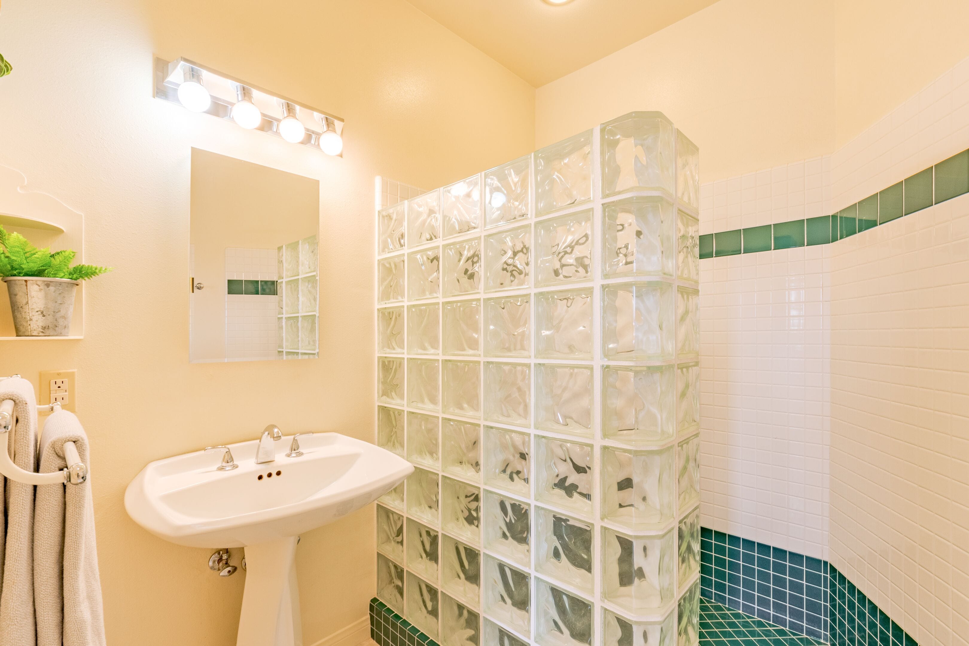 A bathroom with a white sink, a mirror, and a glass shower enclosure.