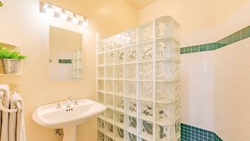 A bathroom with a white sink, a mirror, and a glass shower enclosure.