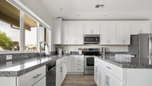 A modern kitchen with white cabinets, granite countertops, stainless steel appliances, and a large window providing natural light. - Luxury Scottsdale Home, walk to Old Town
 (Scottsdale)