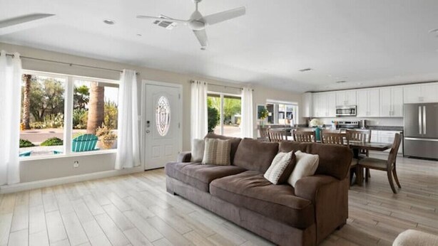 A spacious living room with a brown sofa, a dining area with wooden furniture, and a kitchen with white cabinets and stainless steel appliances. - Luxury Scottsdale Home, walk to Old Town
 (Scottsdale)