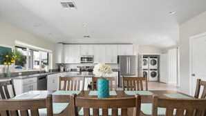 A modern kitchen with white cabinets, stainless steel appliances, and a dining area with wooden chairs and a table. - Luxury Scottsdale Home, walk to Old Town
 (Scottsdale)