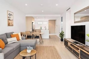 A modern living room with a grey sofa, a small coffee table, and a TV stand.