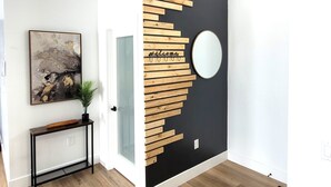 A room with a black and white wall, a wooden wall art piece, a round mirror, and a framed abstract painting. - Luxury Mountain Villa (Show Low)