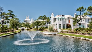 Un grand bâtiment blanc, doté de nombreuses cheminées, avec une fontaine en premier plan.