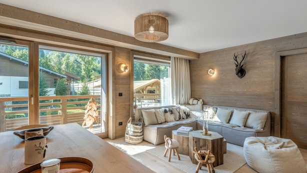 A modern living room with a wooden floor, a large sofa, a coffee table, and a dining table with a tray.
