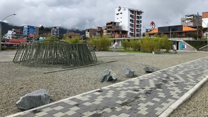An outdoor urban area with a paved walkway, a metal fence, and a variety of buildings in the background. - Edificio San Jose Parque Guatape (Guatapé)
