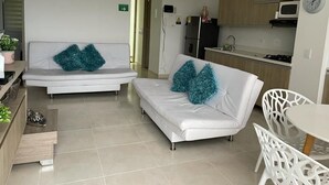 A modern living room with a sofa and chairs, a small kitchen area with a microwave and refrigerator, and a dining table. - Edificio San Jose Parque Guatape (Guatapé)