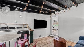 Eine moderne Küche mit Essbereich, einem an der Wand montierten Fernseher und Blick ins Freie.