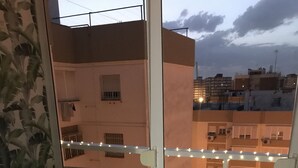 Un balcón con una mesa lista para tomar té, sillas y vistas de edificios vecinos.