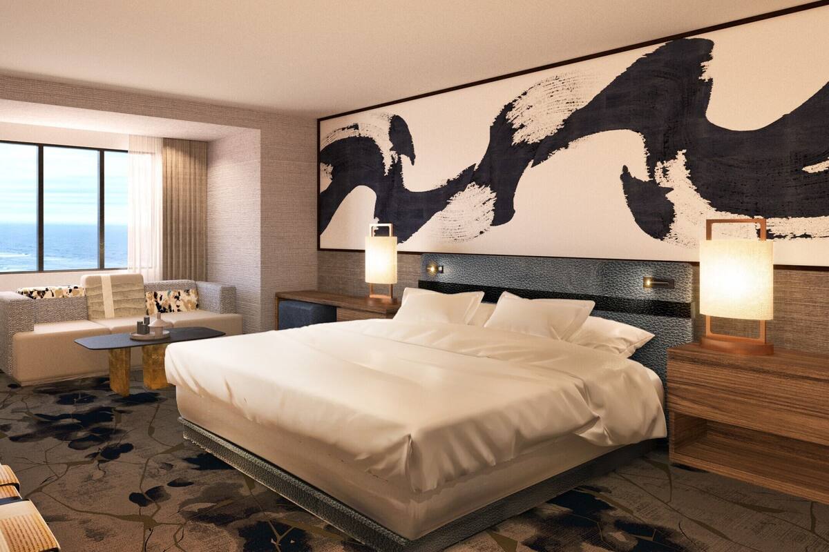 Habitación de hotel con una cama grande, un escritorio, un sofá y vista al océano.