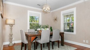 Uma sala de jantar com uma mesa de madeira, seis cadeiras, um tapete estampado e um candelabro.