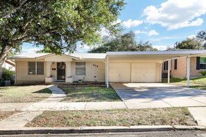 A single-story house with a garage, a covered porch, and a well-maintained lawn.