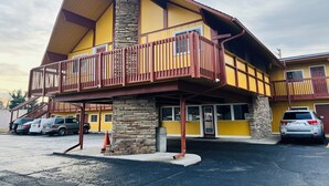 A two-story building with a yellow facade, a stone pillar, and a red balcony. - Clayton House Motel (Loves Park)