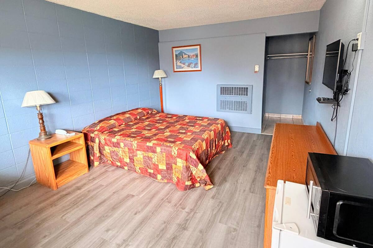 Ein Hotelzimmer mit Bett, Schreibtisch, Lampe, Fernseher und Heizung.