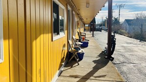 A yellow building with a covered porch, outdoor seating, and a motorcycle parked outside. - Clayton House Motel (Loves Park)