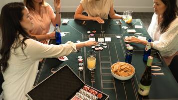 A group of people playing blackjack at a casino table with chips, cards, and drinks.