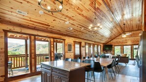 Una cabaña de madera espaciosa con un amplio comedor, cocina y un balcón con vistas panorámicas a la montaña.