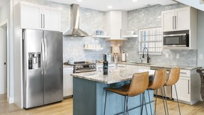 A modern kitchen with a stainless steel refrigerator, a built-in oven, a microwave, and a large island with bar stools. - Restful Getaway with Boat Parking, Hot Tub, Free Attraction Tickets & 1 Mile to State Park Marina (Branson)