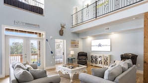 A spacious living room with a high ceiling, a balcony, and a mounted deer head. - Restful Getaway with Boat Parking, Hot Tub, Free Attraction Tickets & 1 Mile to State Park Marina (Branson)