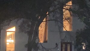 Um edifício com uma grande porta em arco e luz interior visível.