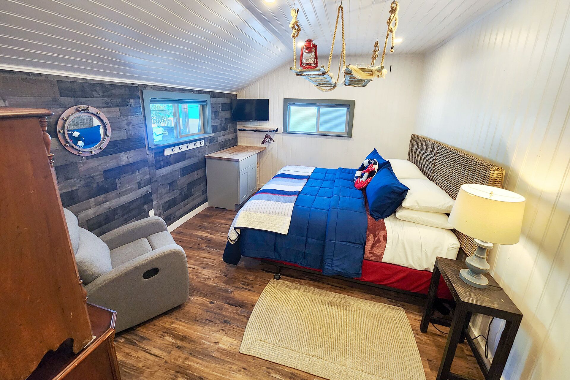 Une chambre à coucher comprenant un lit, un bureau, une chaise, une fenêtre et un téléviseur fixé au mur.