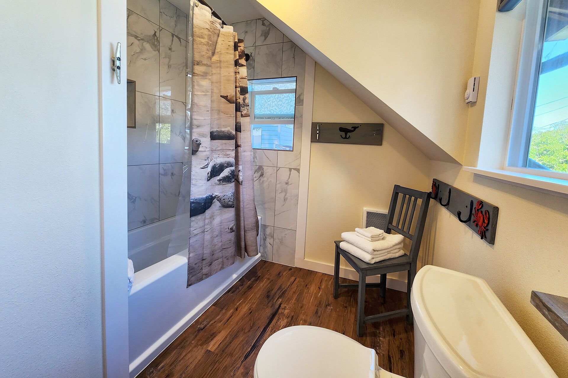 A bathroom with a shower, a toilet, and a chair.