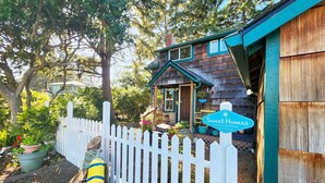 A rustic wooden house with a white picket fence, a sign for Sweet Homes Vacation Getaways, and a mailbox.