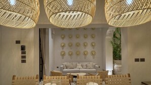 A dining area with a large table, wicker chairs, a glass pitcher, and a wall decorated with hats. - Casa Antal  -  Yucatan Home Rentals (Mérida)