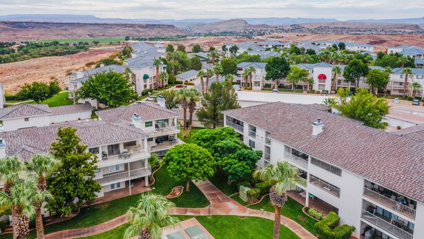 A residential area with multiple two-story buildings, each featuring balconies and a central courtyard with trees. - Las Palmas 326, Resort pool and clubhouse, Private balcony (Saint George)