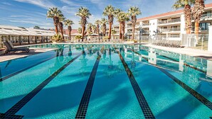 A clear swimming pool with multiple lanes, surrounded by palm trees and a hotel building with balconies. - Las Palmas 326, Resort pool and clubhouse, Private balcony (Saint George)